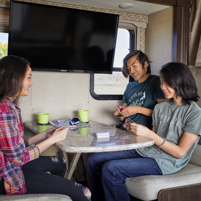 Group of young adults sitting inside of an RV playing cards