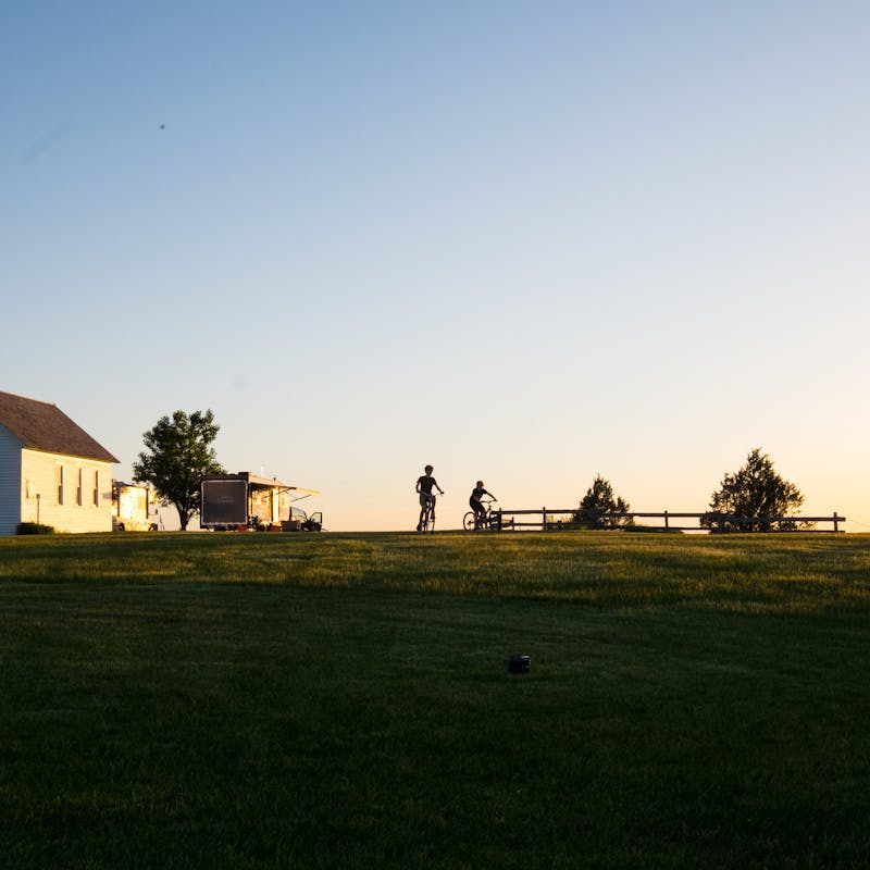 Gretchen Holcomb's kids ride their bikes in a prairie homestead where their RV is parked.