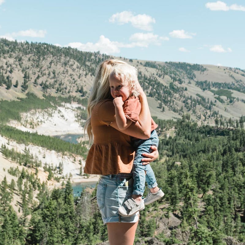 Mother holds young boy and hugs him in front of mountain scene