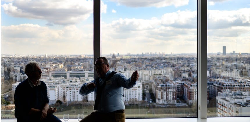 Men in high rise office building having a discussion with cityscape in background