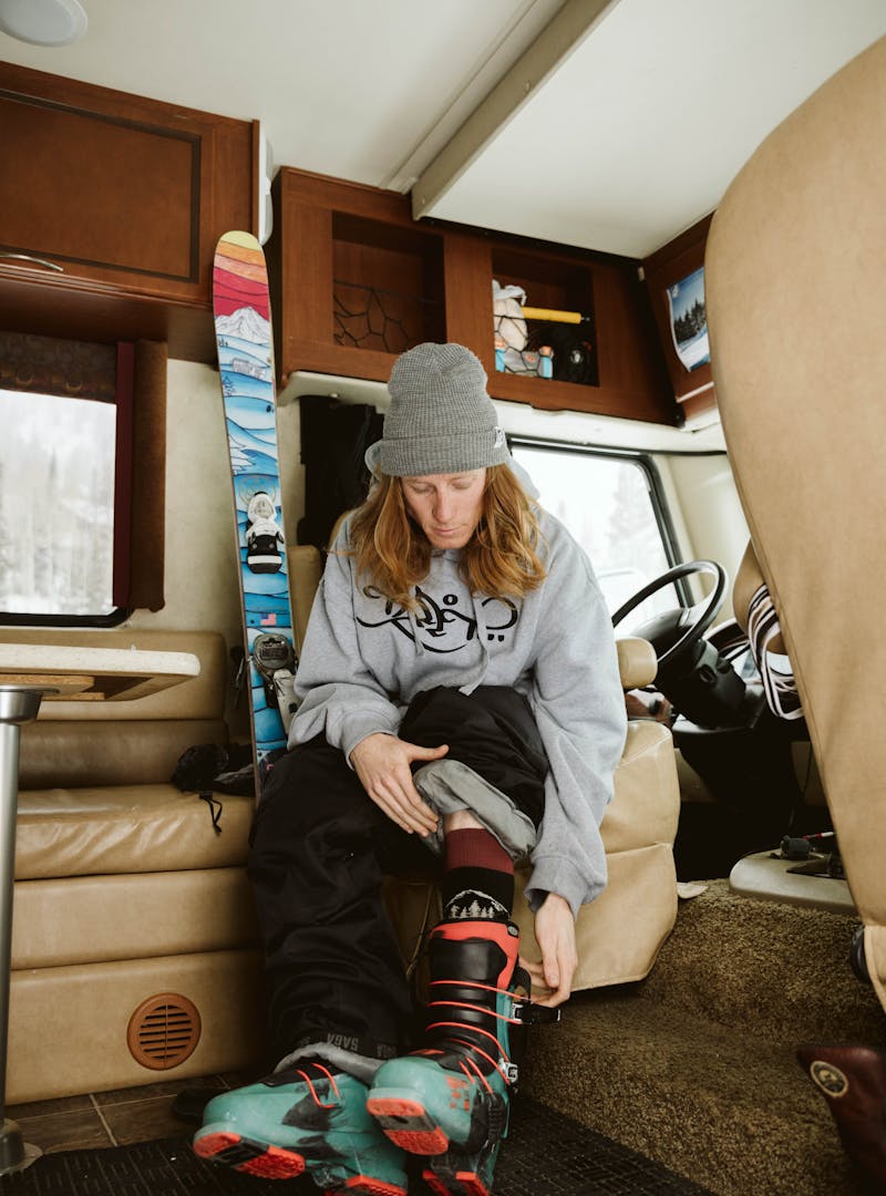 Ryan putting his ski boots on inside his RV.