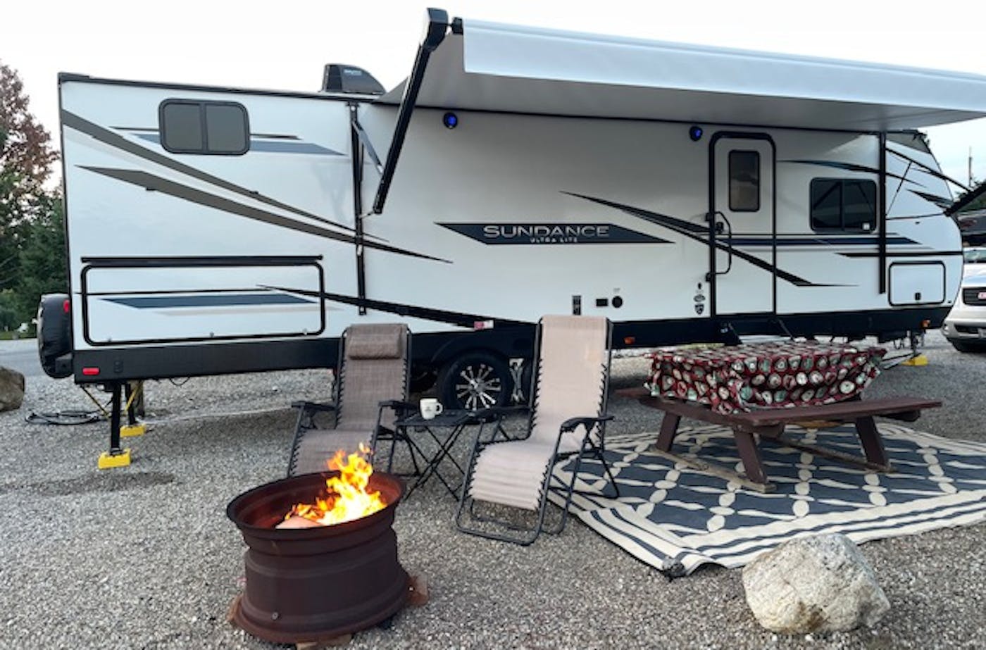 Brandy Gleason's Sundance RV at a camping site with a campfire lit at a safe distance from the RV
