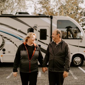 David and Kathy Boland holding hands outside their parked Thor RV.