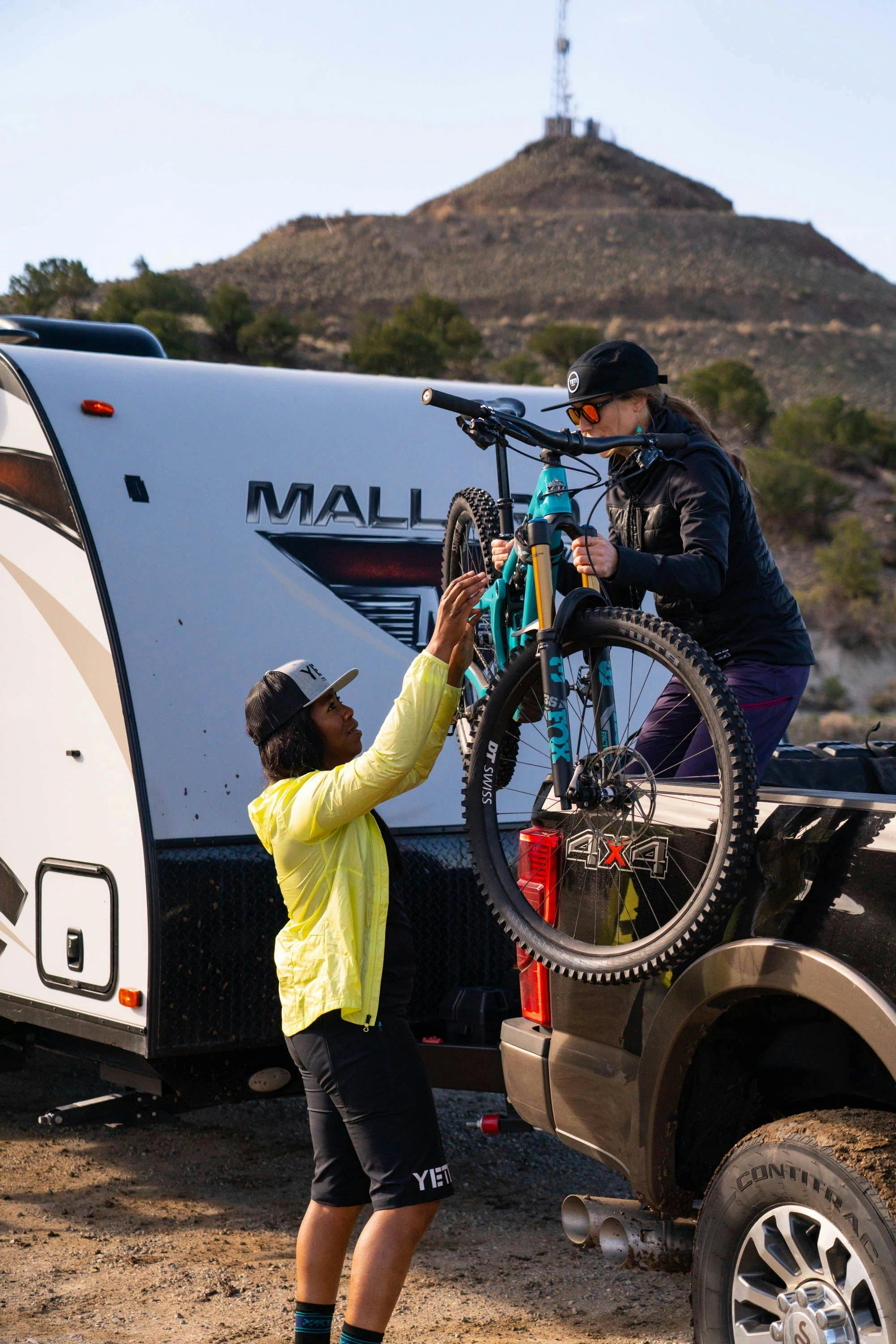 Britt Greer passes Brooke Goudy a mountain bike out of a truck