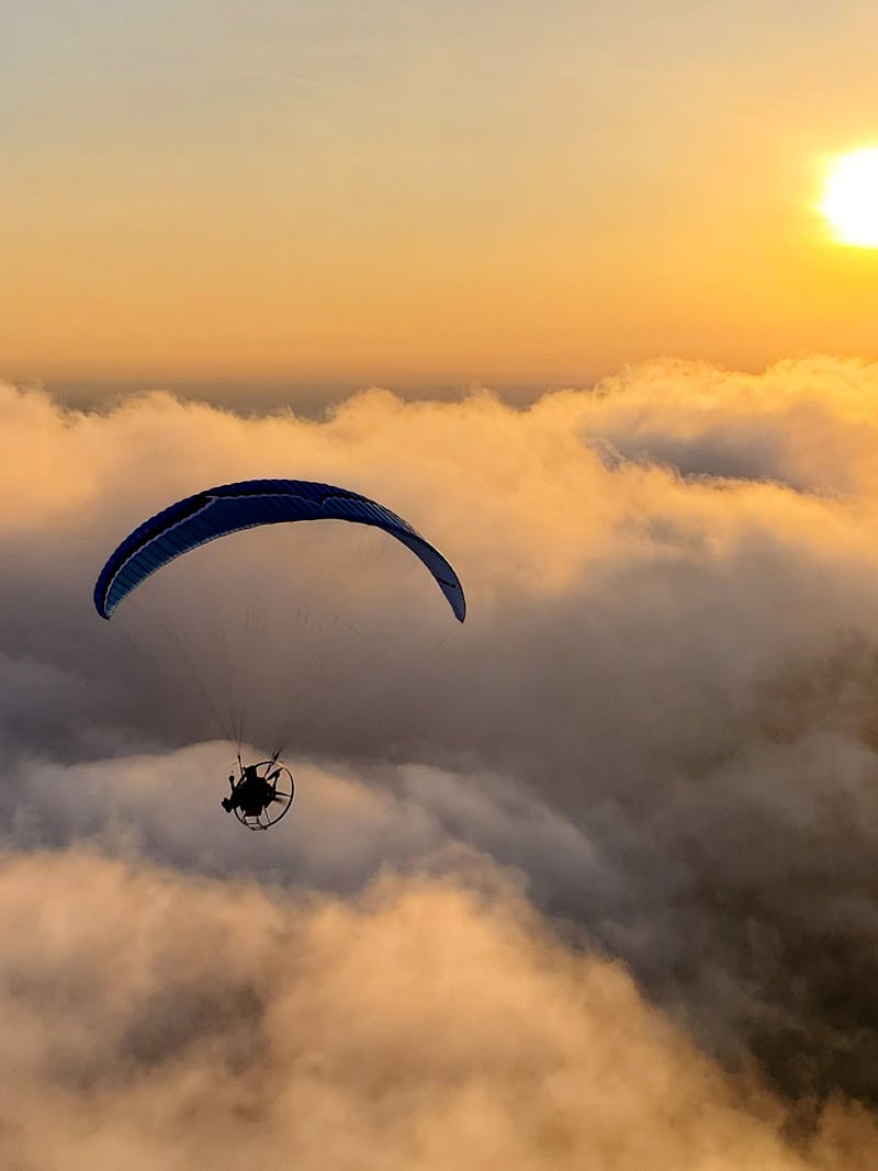 Tucker Gott paramotors over the clouds at sunset.