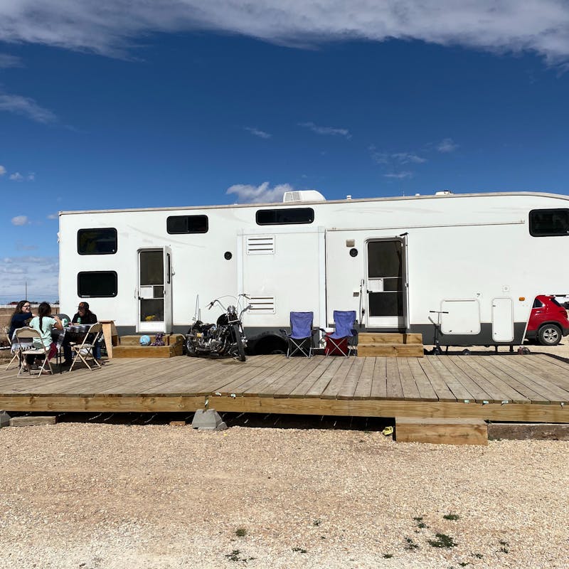 An RV parked at a desert campsite with an outdoor patio.