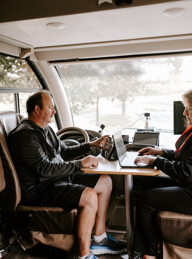 David and Kathy sitting at an RV desk with a laptop and a tablet.