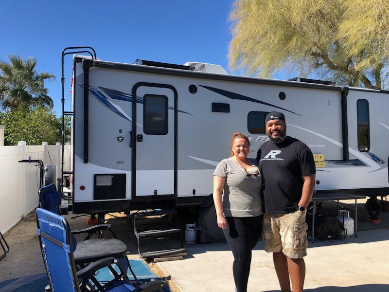 Ben and Christina McMillan pose in front of their travel trailer RV 