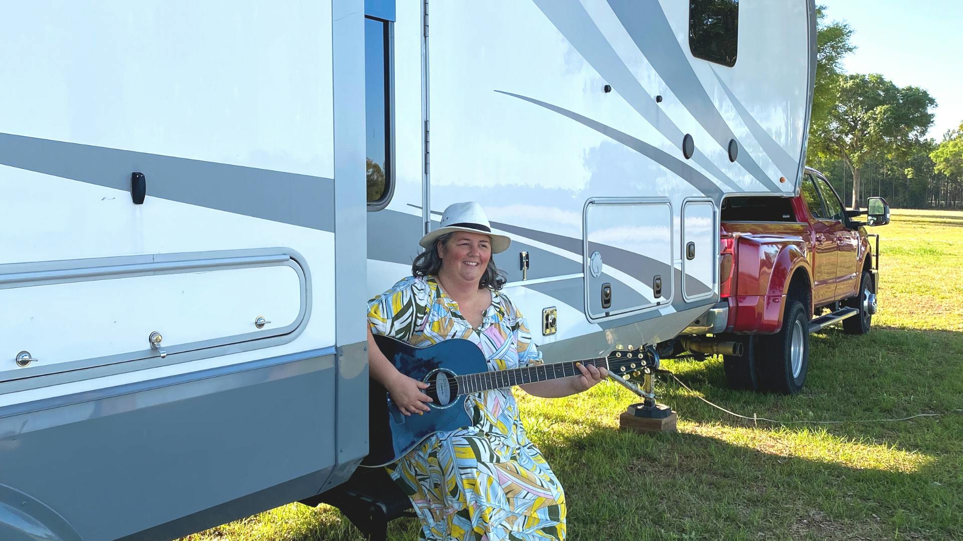 Kimberly Graham playing guitar on the staris of her RV at the Grey Fox Bluegrass Festival
