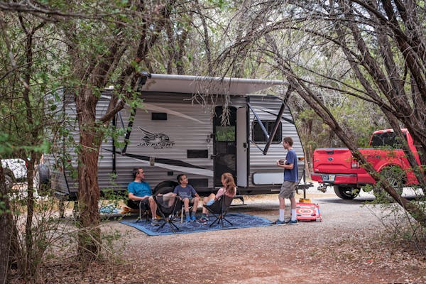 Alison Takacs and her family sitting in front of their RV at their campsite in Dinosaur Valley State Park