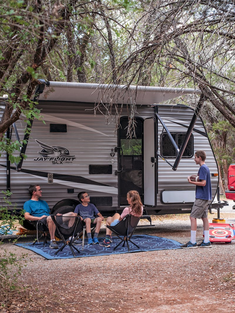 Alison Takacs and her family sitting in front of their RV at their campsite in Dinosaur Valley State Park