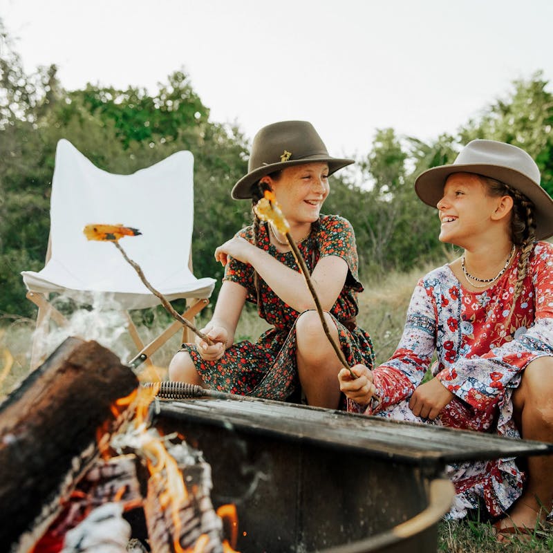 Girls smiling as they cook shrimp over a fire
