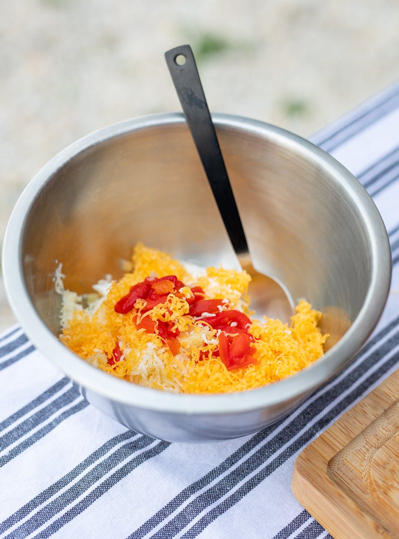 Mixing cheese and pimentos together in a bowl.