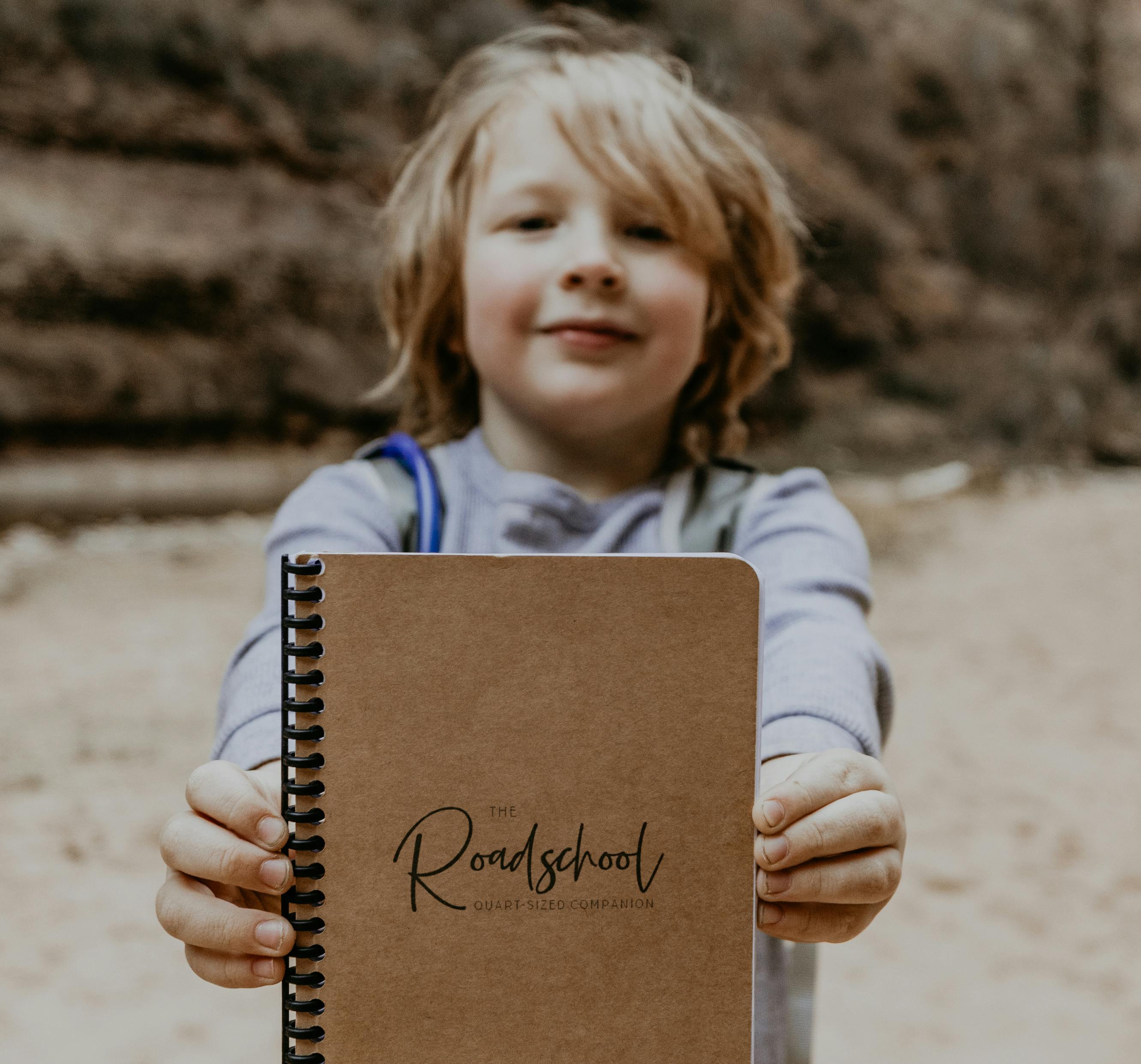 Andy and Kristen Murphey's son holding up a Roadschooling Notebook