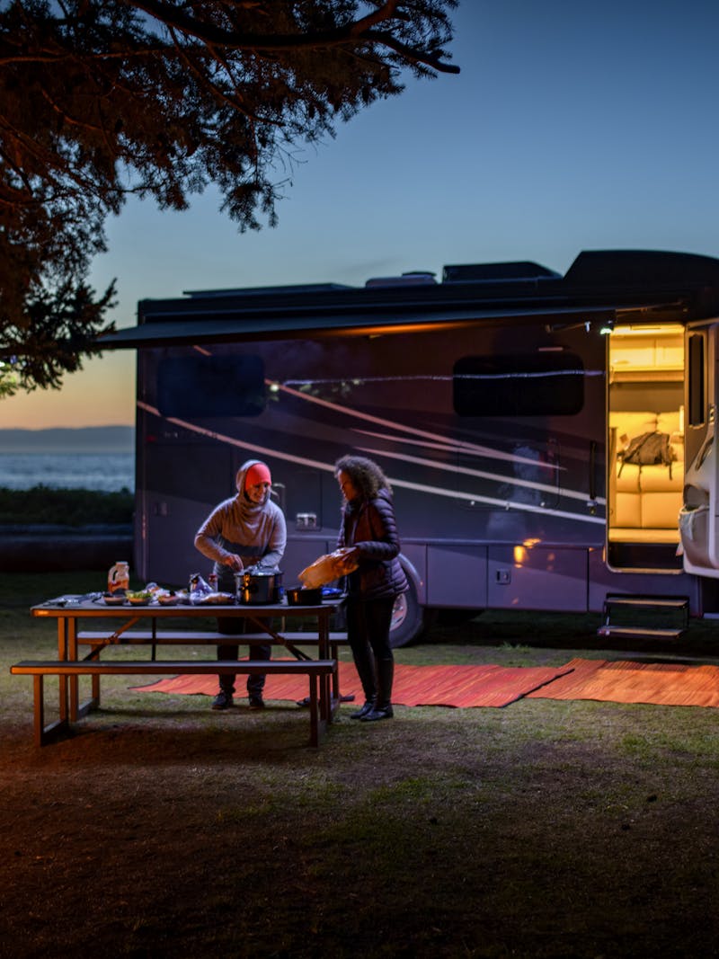 Chelsea and Layla cook dinner at dusk outside of a Tiffin Wayfarer RV