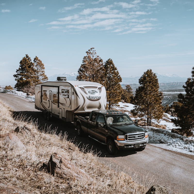 A truck towing a Jayco RV on a mountain road.