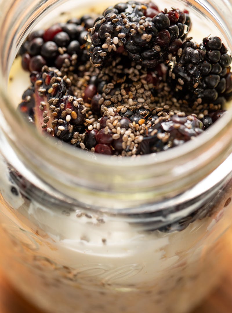 A close up shot of blackberries and chia seeds on top of overnight oats.