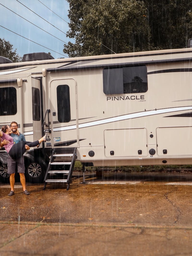 Holly Miner's husband holding her in the rain with their Jayco Pinnacle behind them.