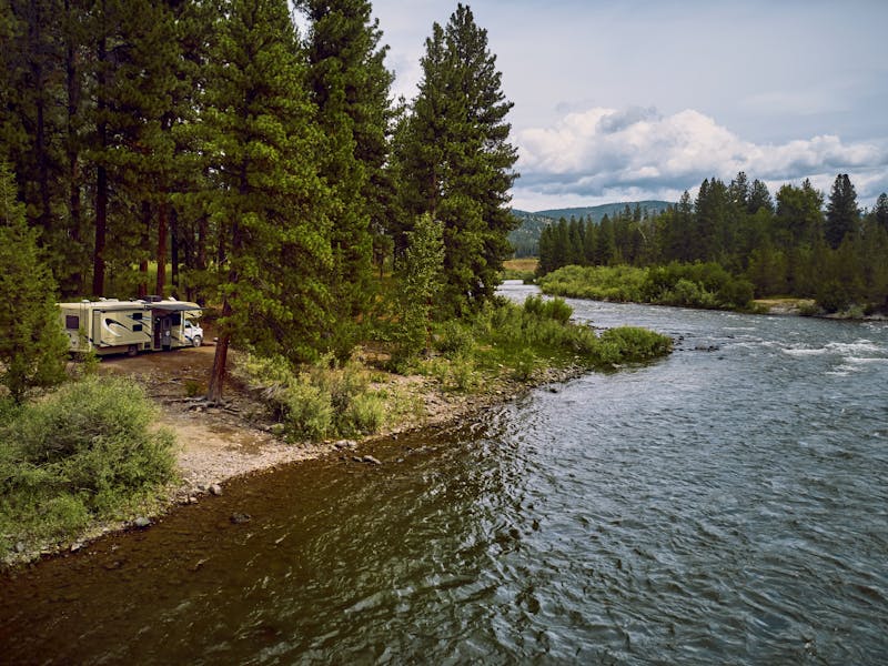 An RV parked next to a river.