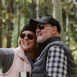 A headshot of Tina and Craig posing in the woods.