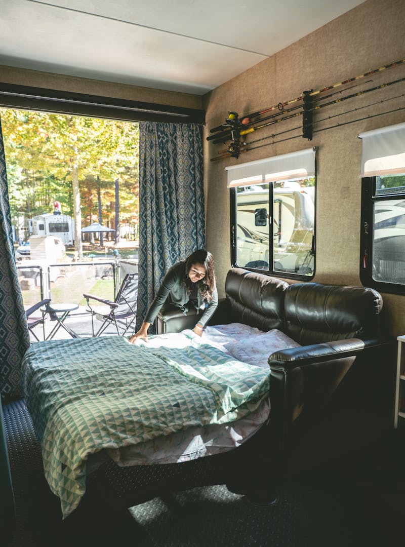 Sandra making the bed on the pull-out couch that transforms the garage to a bedroom.