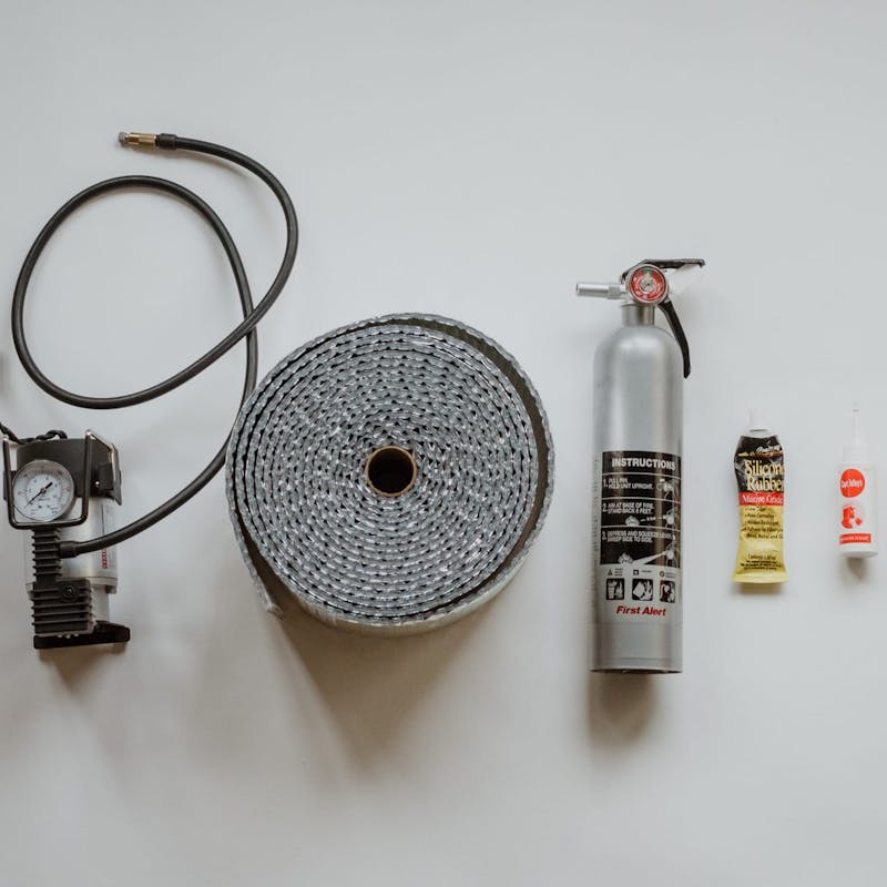 Shot of various RV essential items, including tire pressure gauge, fire extinguisher, glue and tape