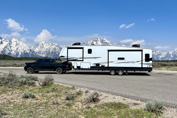 Bailey and Nicole Damberg's Dutchmen Astoria fifth wheel with a truck and the Grand Teton Mountains the background.