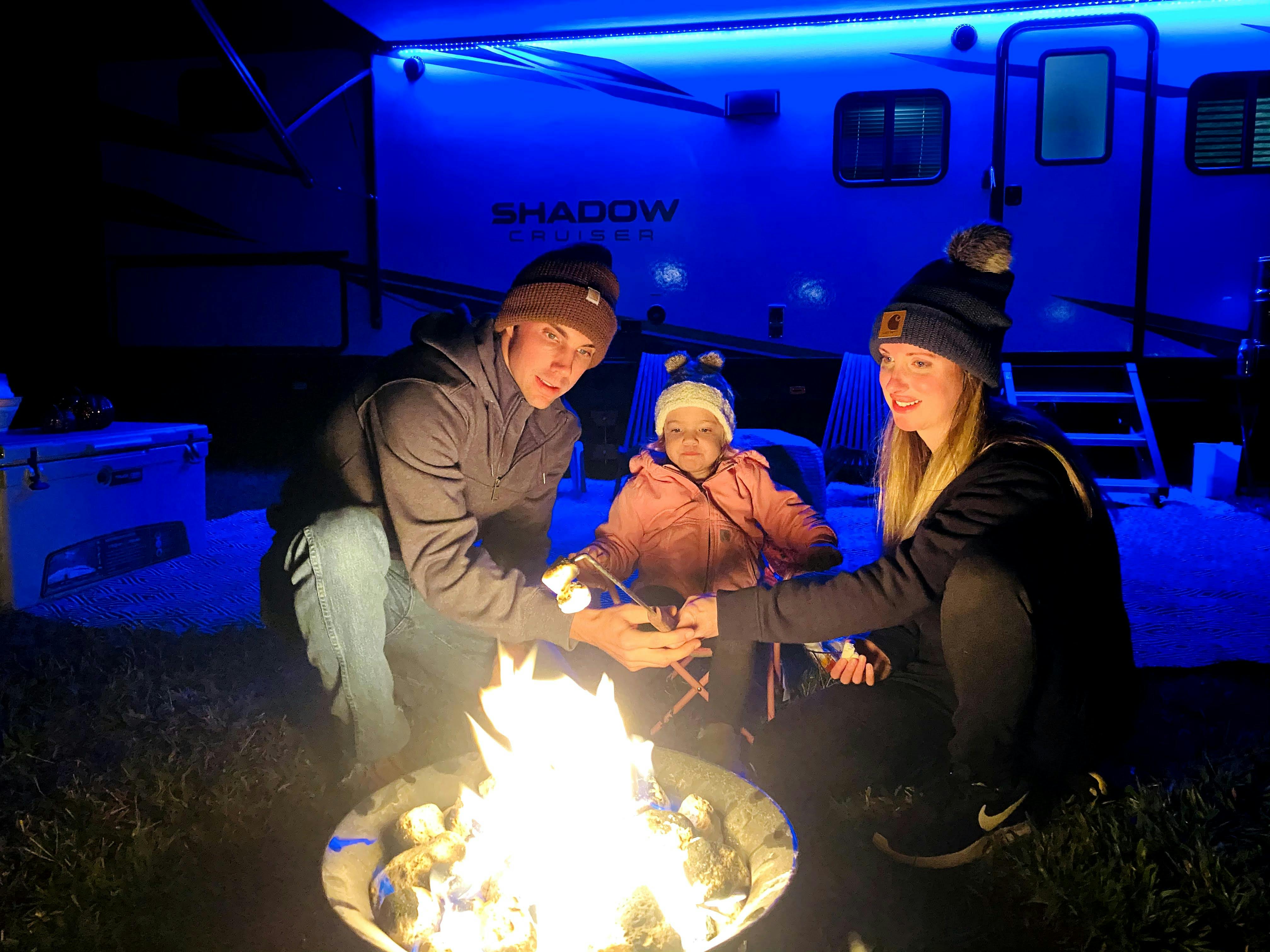 John King sitting around a campfire with his daughter and wife, while at campsite with his Shadow Cruiser travel trailer.