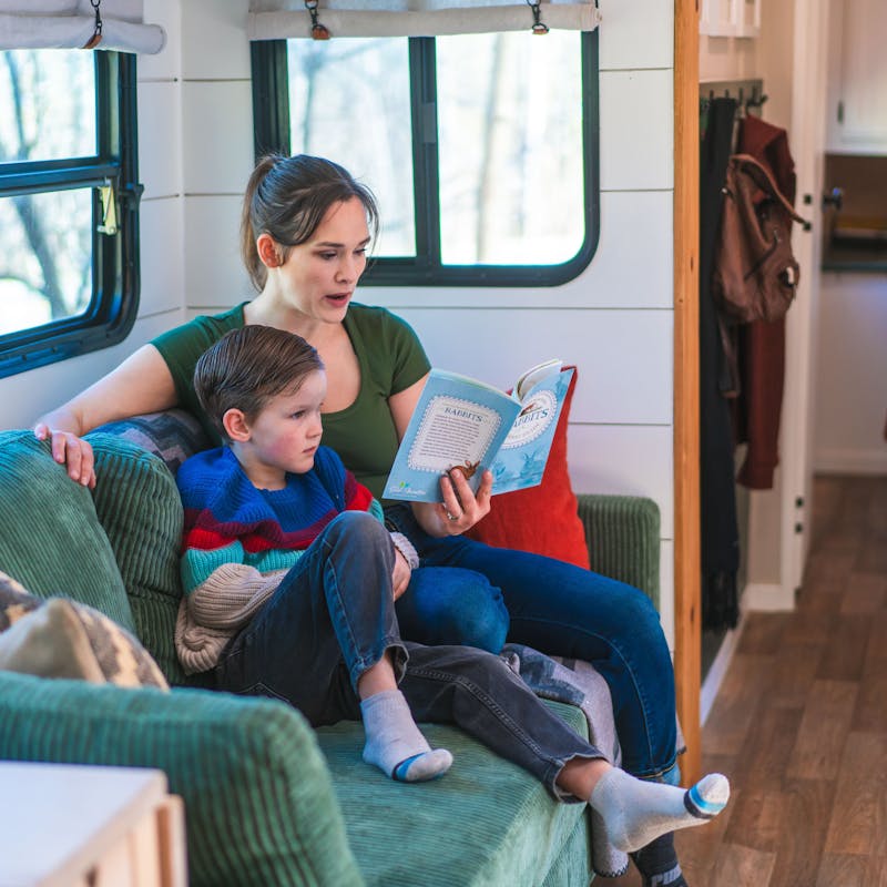 Renee Tilby reads to her son on the couch inside their Jayco Jay Flight travel trailer.