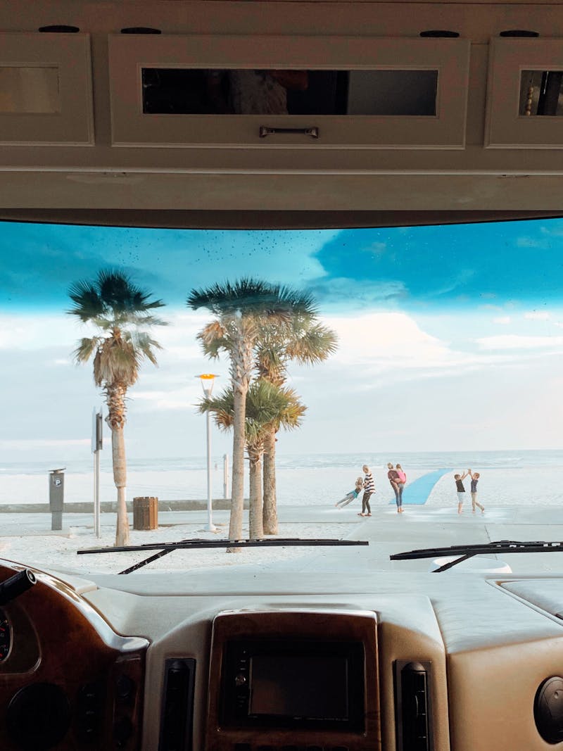 View out front windshield of palm trees, ocean, waves, and family playing in Gulf Shores, Alabama