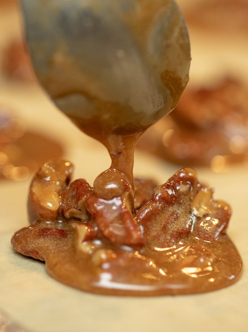 Dropping pralines by the spoonful onto parchment paper.