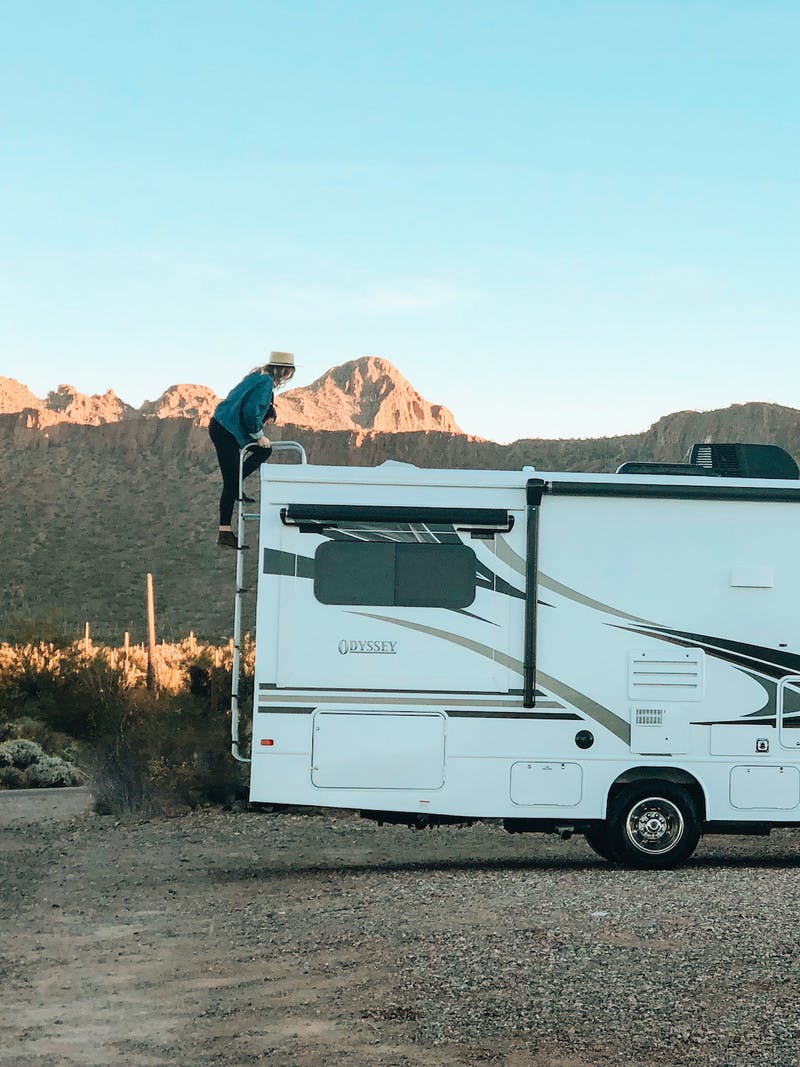 Natalie Allen climbing on top of Entegra Class C RV in the desert.