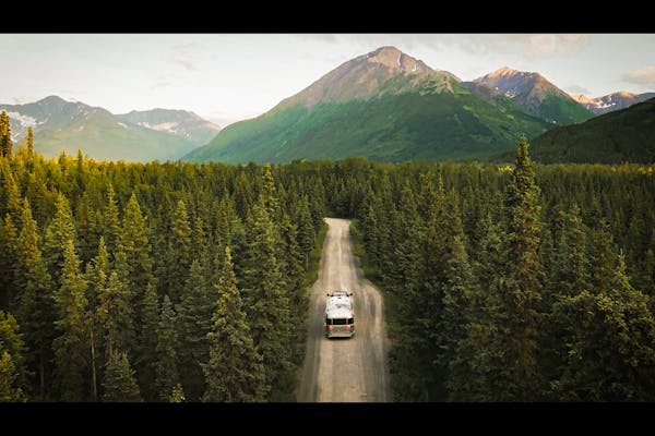 Stacey Power's Airstream driving through a forest towards a mountain