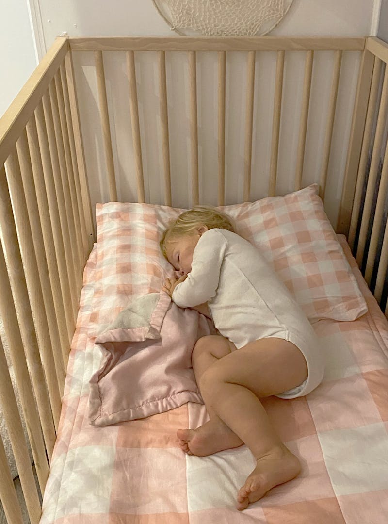 A young child asleep in a crib.