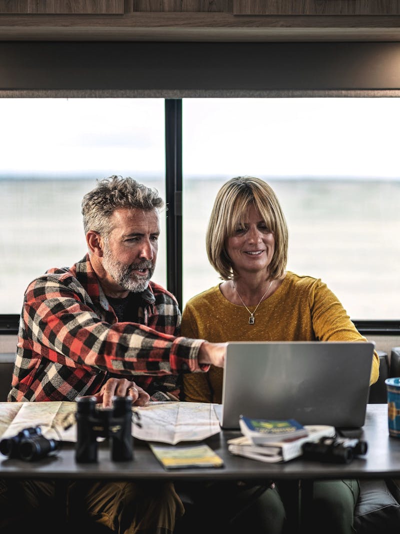 A couple pointing and looking at things on a computer