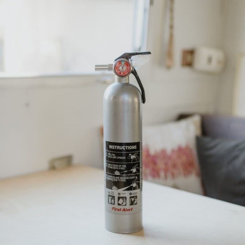 Silver fire extinguisher sitting on white table
