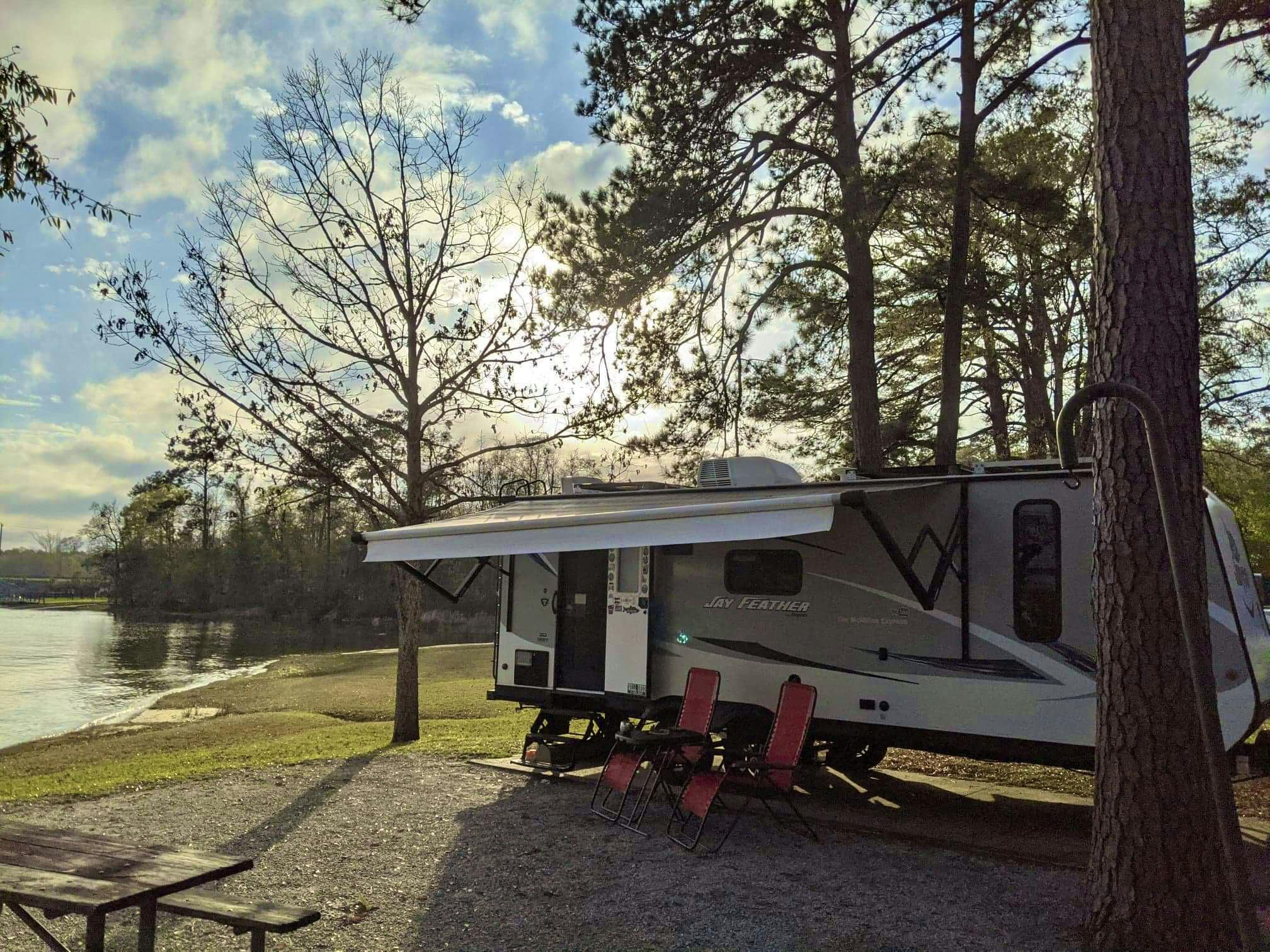 CHRISTINA AND BEN MCMILLAN's Jayco Jay Feather parked at a traditional campground next to a lake 