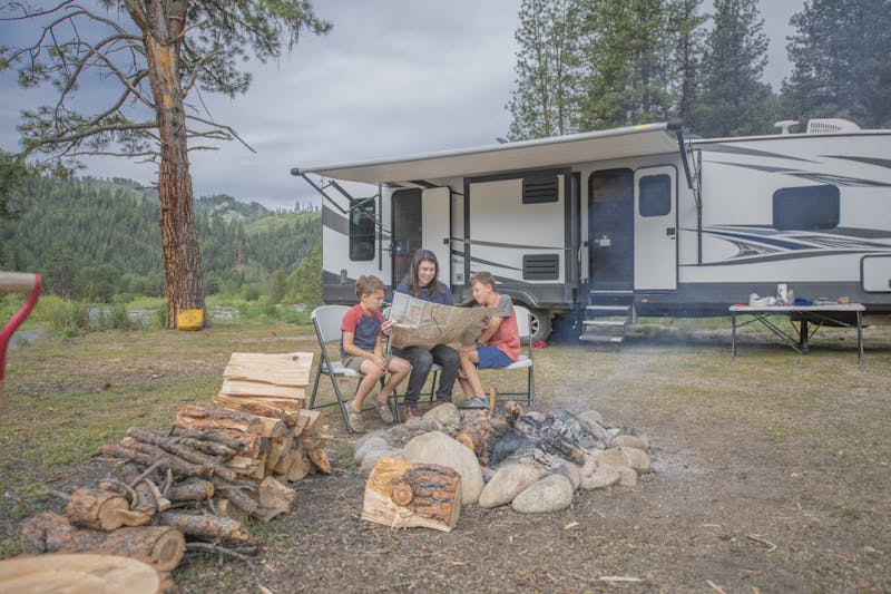Chelsea Day looking at a map with her children in front of her Highland Ridge RV