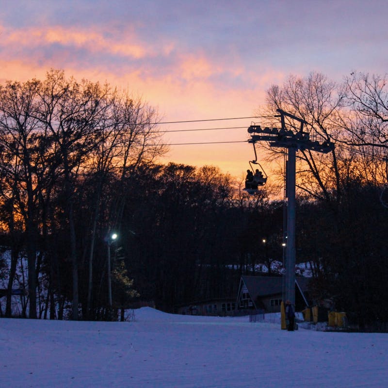 Cascade Mountain ski lift, chair with skiers and a sunset