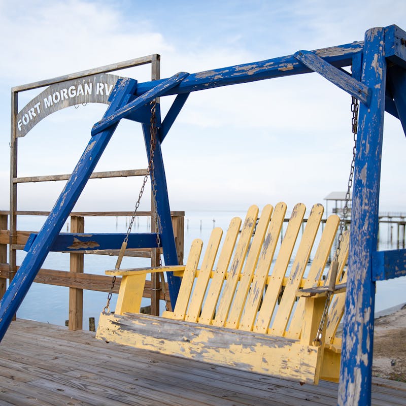 A wooden swing positioned on a dock overlooking the water.