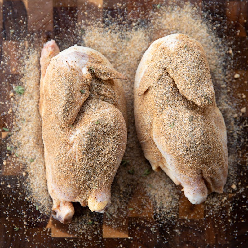 Two halves of a small Cornish hen, dusted with spices.