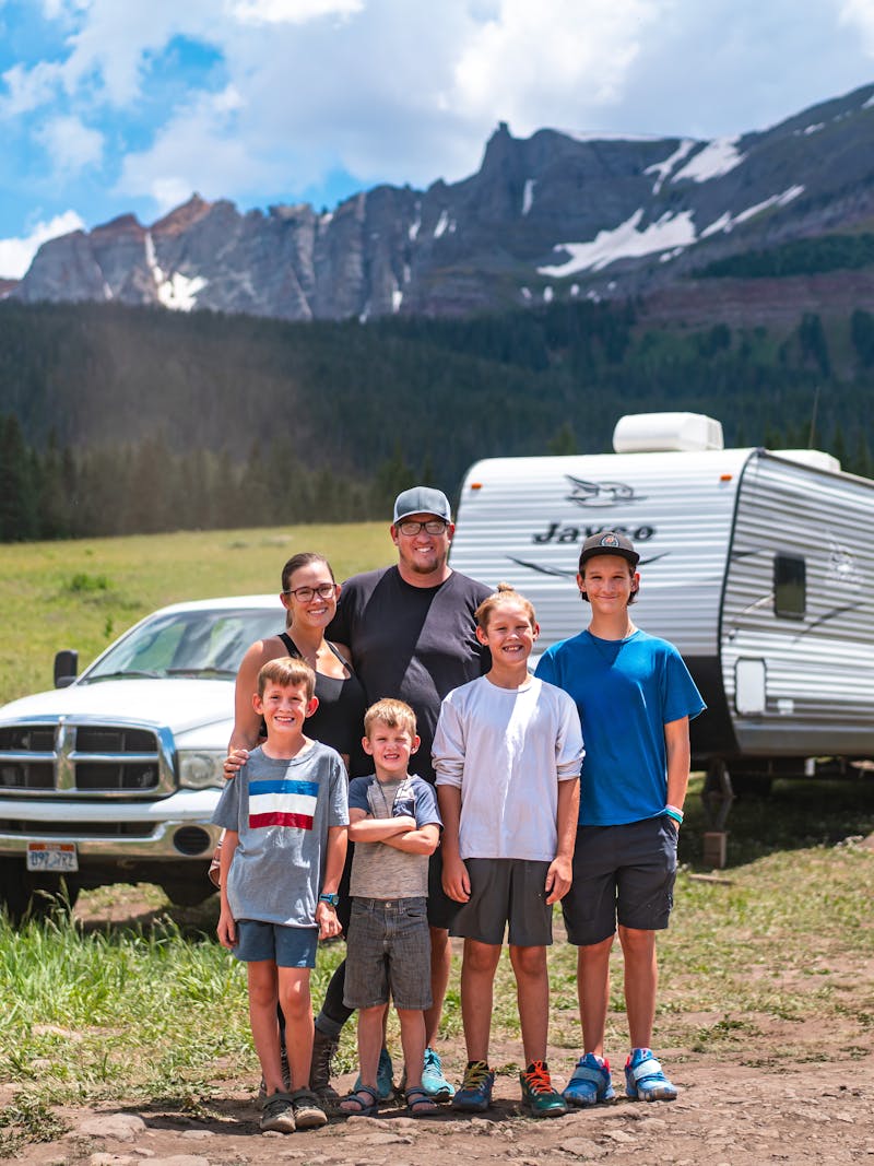 The Renee and Shaun Tilby family and their four kids standing in front of their Jayco Jay Flight in a mountain landscape in Telluride.