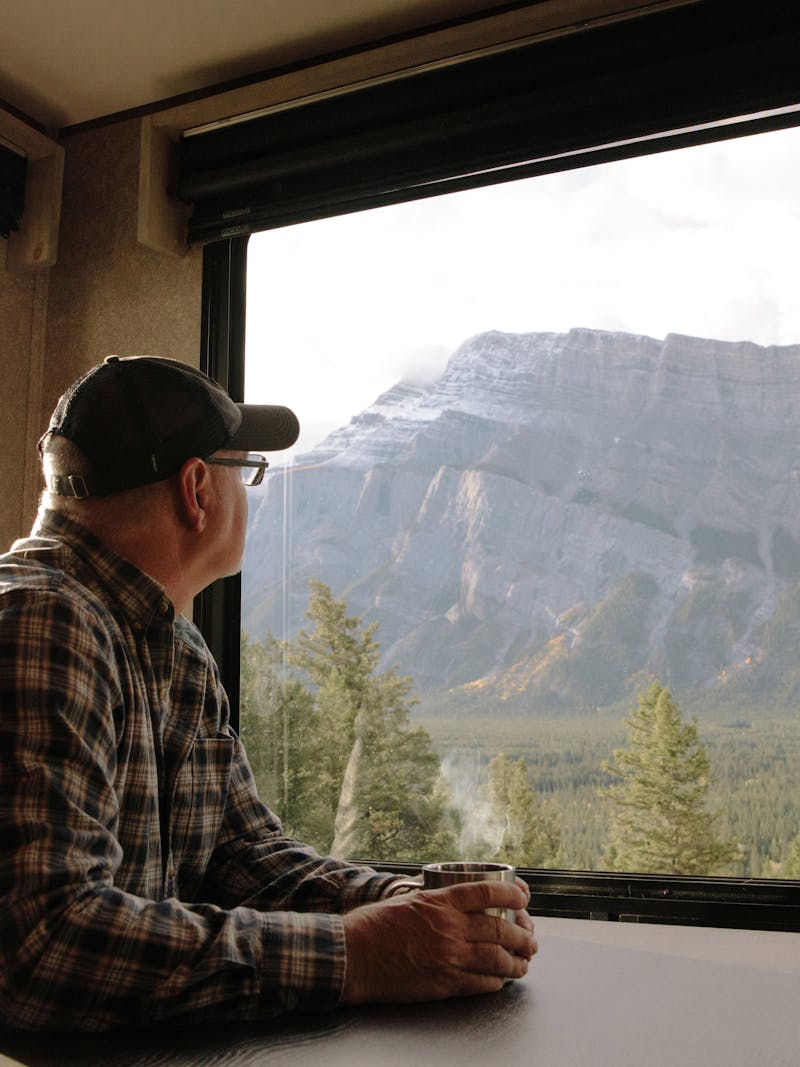 Craig Klinefelter enjoying a cup of coffee as he looks out the window at the mountains of Banff. 