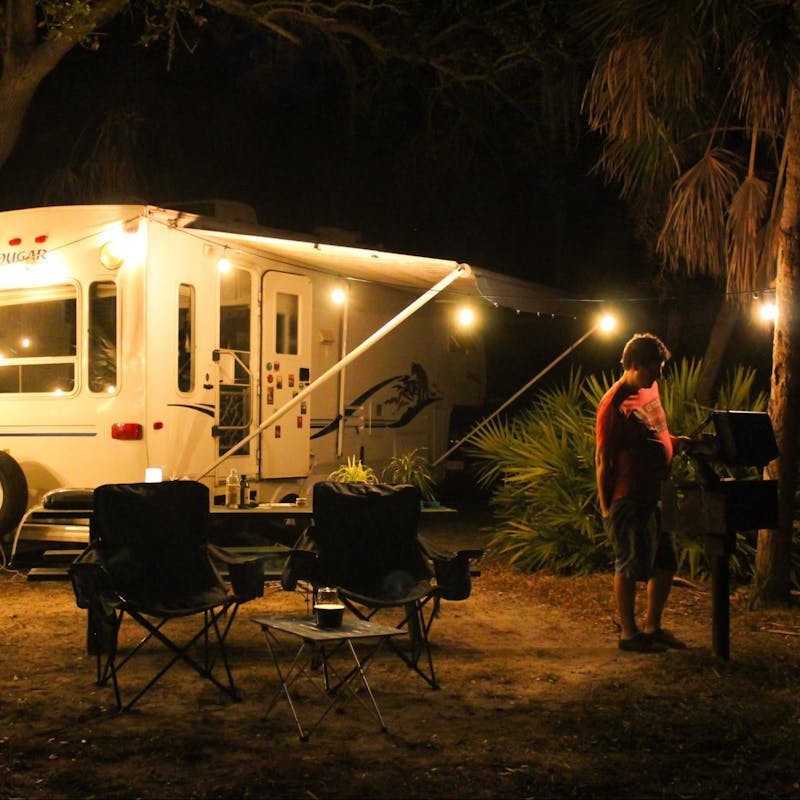 Jesse & Rachael Lyons' cook at a grill at their campsite in front of their Keystone Cougar RV.