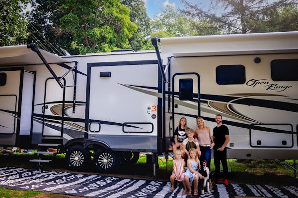 The Cassie and Joshua Bailey family pose in front of their Highland Ridge Open Range Fifth Wheel.