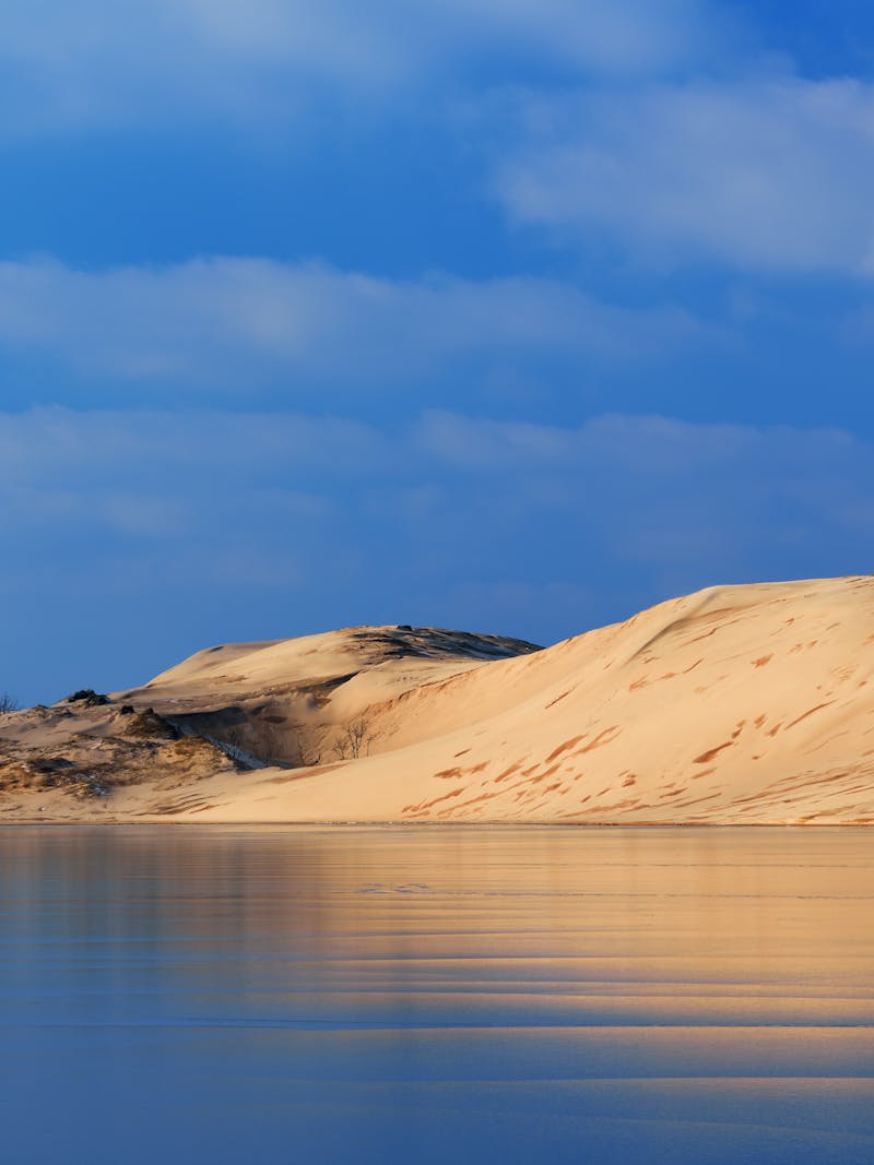 A sand dune reflects in a nearby lake. 