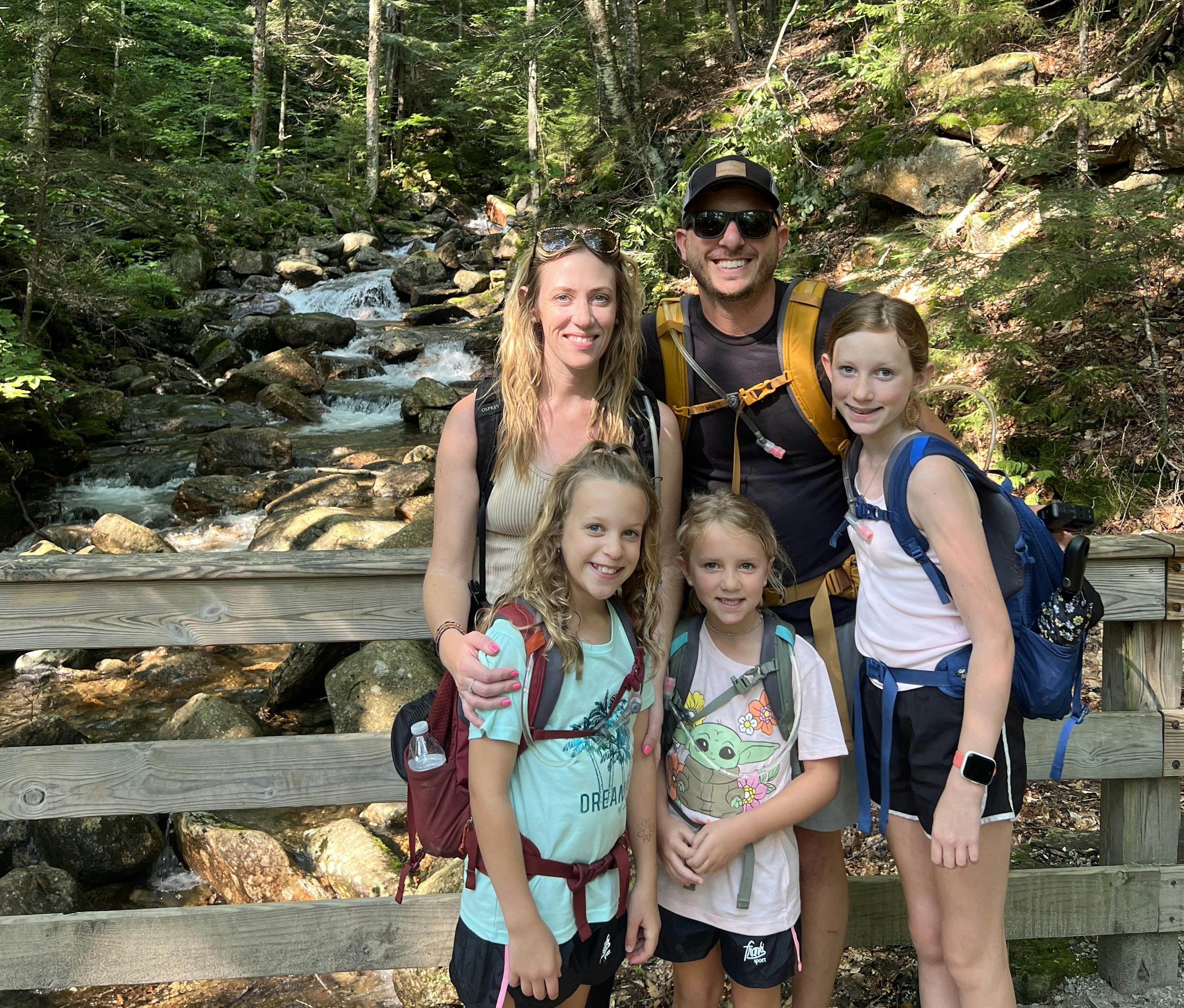 Rob and Ashley Peeples family on a bridge over a mountain stream