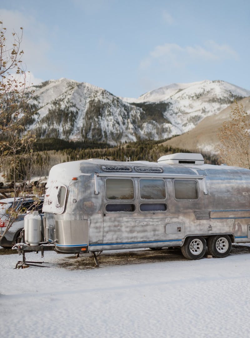 Airstream in the snow with snowy mountains in the background