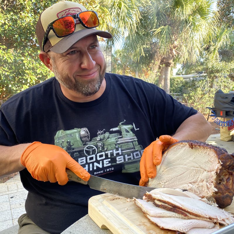 Abby Booth's husband cuts into a Turkey for thanksgiving outside their Dutchmen Kodiak travel trailer.