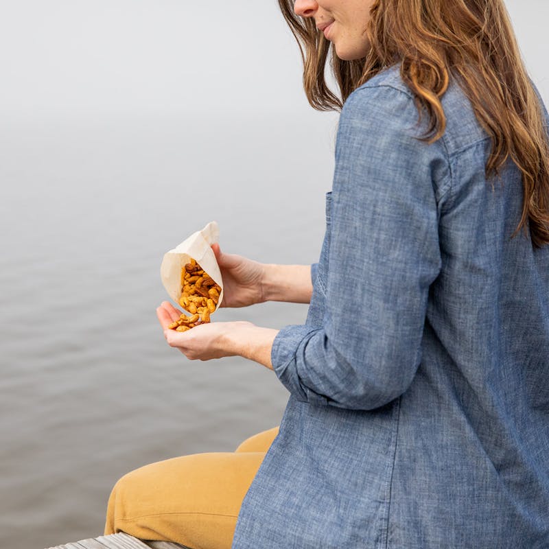 Aubrey eating mixed nuts on a dock while dangling her feet in the water.